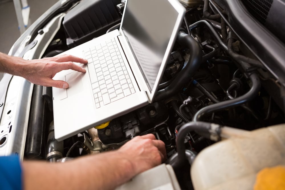 Mechanic using laptop on car at the repair garage